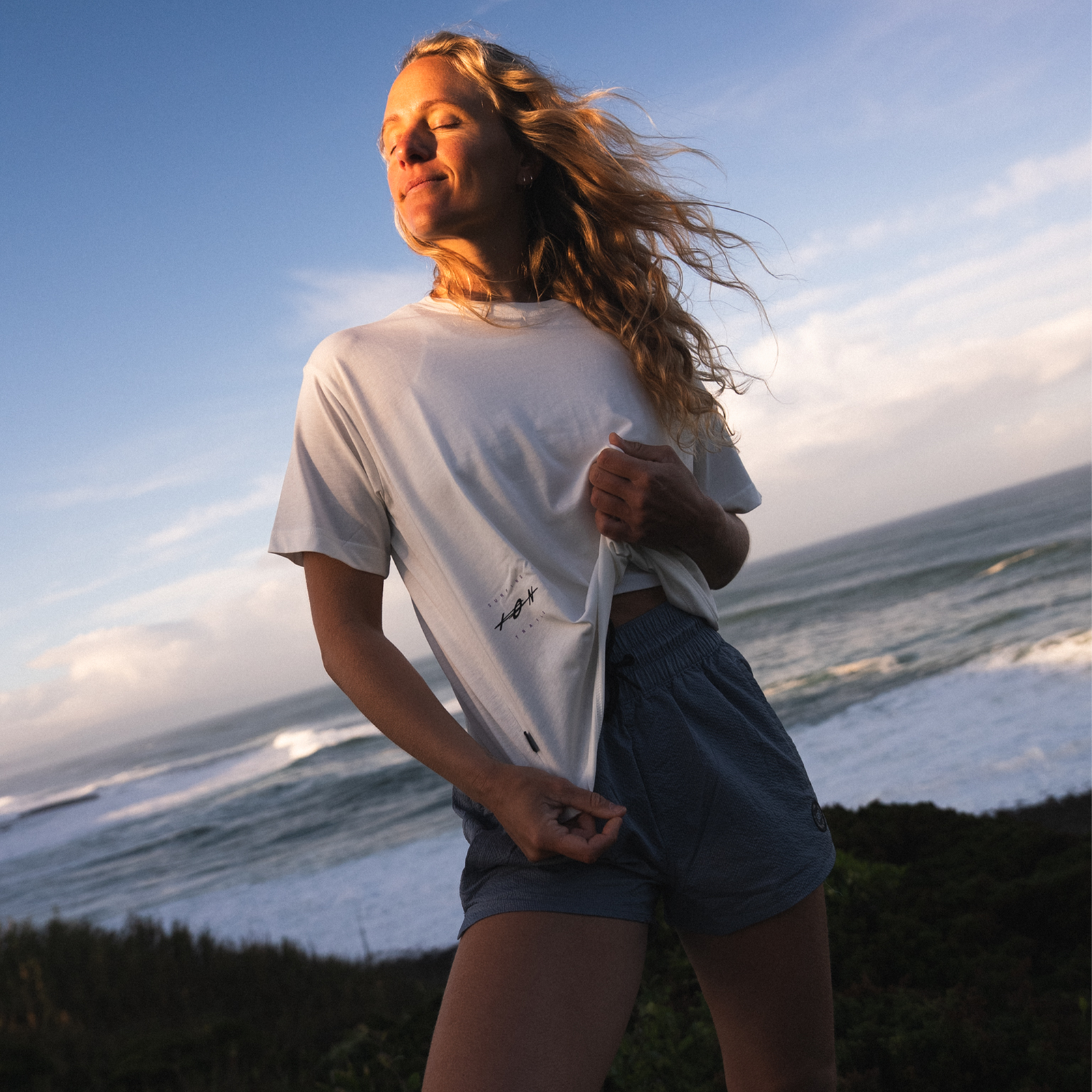 ION Vibes SS women's t-shirt in off-white worn at the coast during golden hour