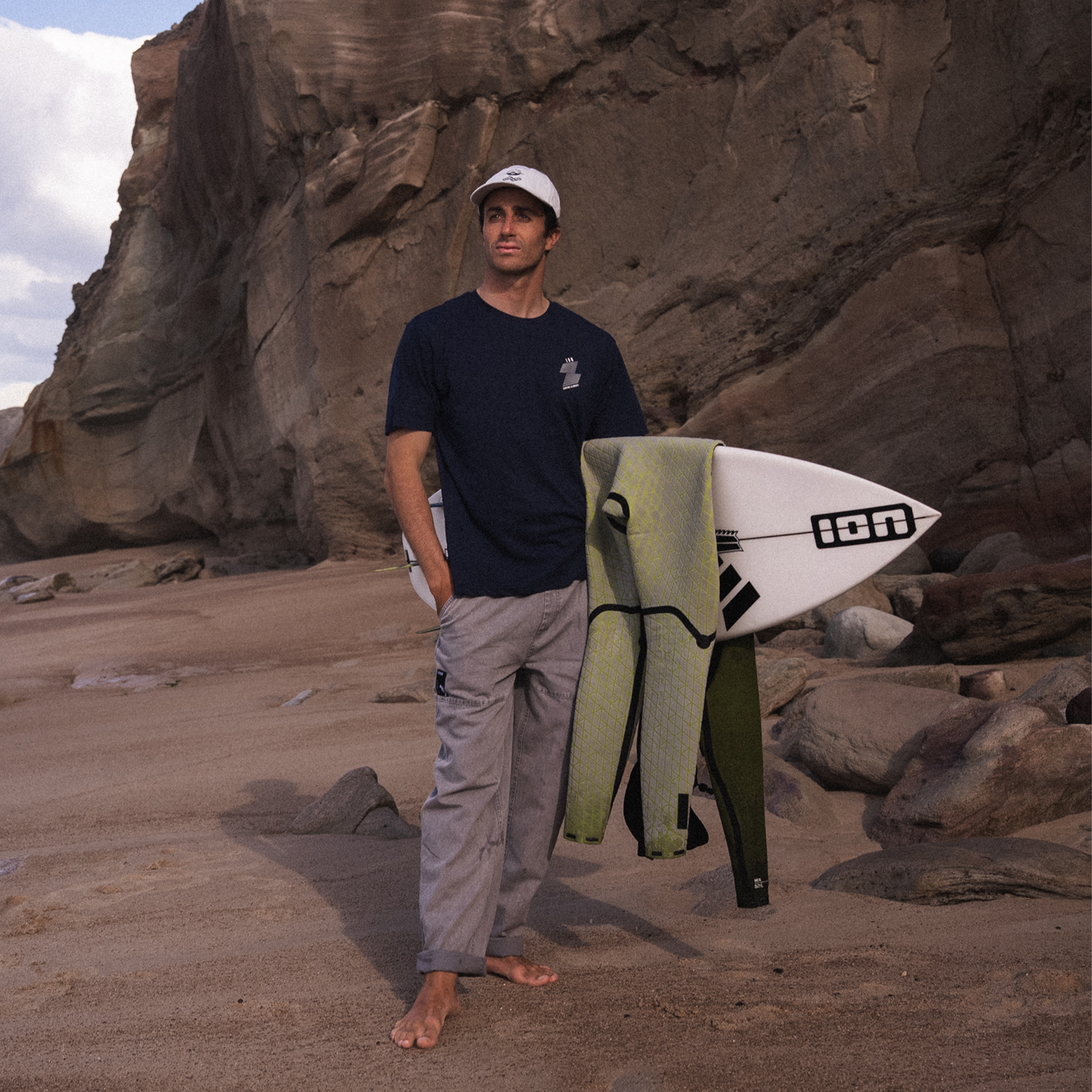 ION Pants HD Cotton pantaloni unisex in grigio pietra durante una sessione surf su spiaggia rocciosa