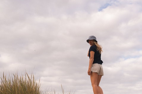 ION Ionic women's boardshorts in sand beige during a coastal beach lifestyle moment on dunes