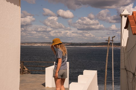 ION Bucket Hat in gold burst worn at a coastal terrace overlooking the ocean