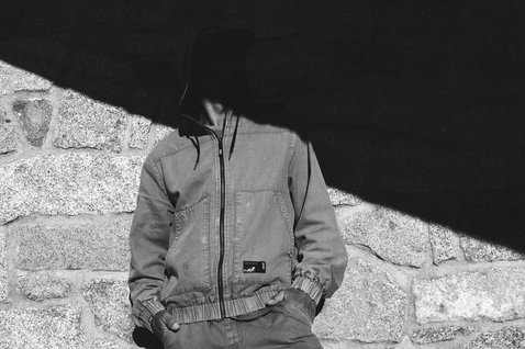 ION Jacket HD Insulated Cotton unisex jacket in charcoal worn against a stone wall