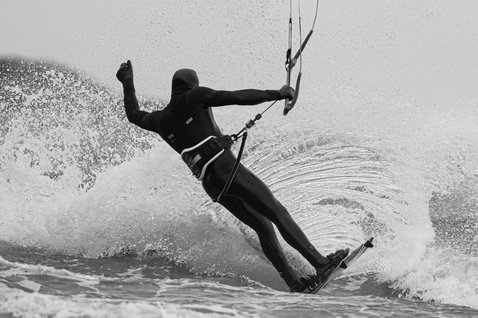 ION Seek Amp 6/5mm hooded front-zip fullsuit in black during kitesurfing on the ocean