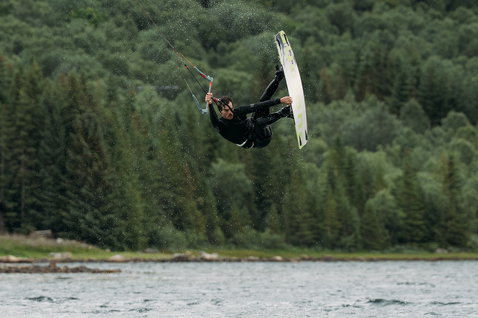 ION Seek Amp 5/4mm front-zip fullsuit wetsuit in black during kitesurfing on a mountain lake