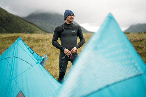 ION Seek Amp 3/2mm front-zip fullsuit in black during kitesurfing in Nordic mountain landscape