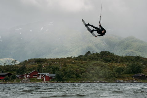 ION Seek Amp 3/2mm front-zip fullsuit in black during kitesurfing on a Norwegian fjord