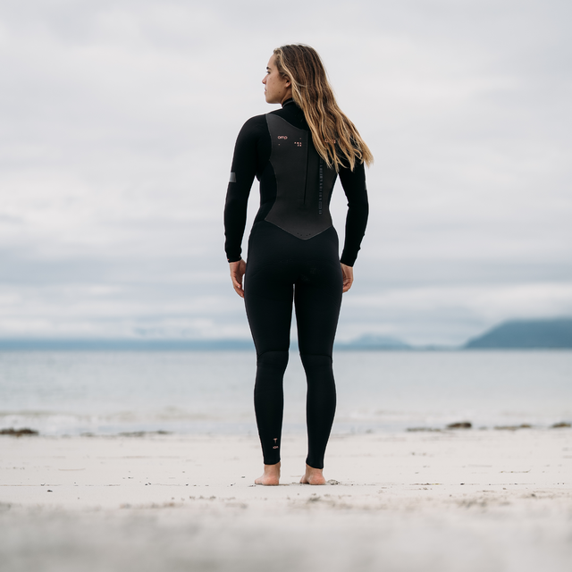 ION Amaze Amp 5/4mm back-zip fullsuit women in black – back view at the coast