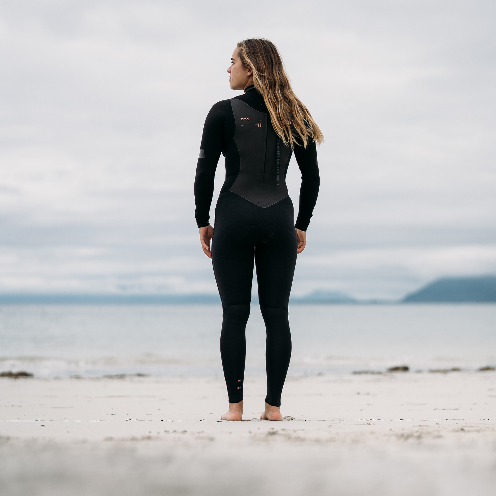 ION Amaze Amp 4/3mm back-zip women's fullsuit in black, back view at the coast