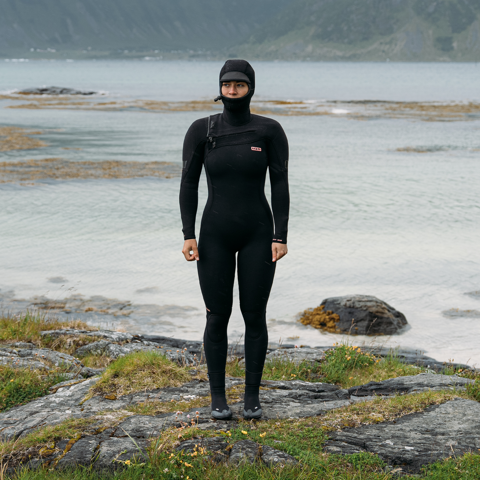 ION Amaze Amp 6/5mm hooded front-zip fullsuit wetsuit in black during surfing at the coast