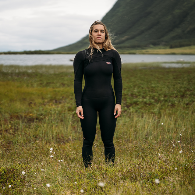 ION Amaze Amp 5/4mm front-zip women's fullsuit wetsuit in black worn in a Nordic highland landscape