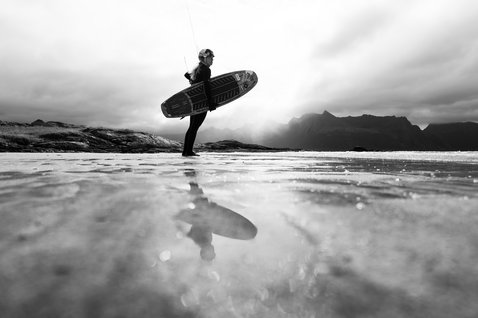 ION Amaze Amp 5/4mm front-zip women's fullsuit wetsuit during wave riding at a rocky northern coastline
