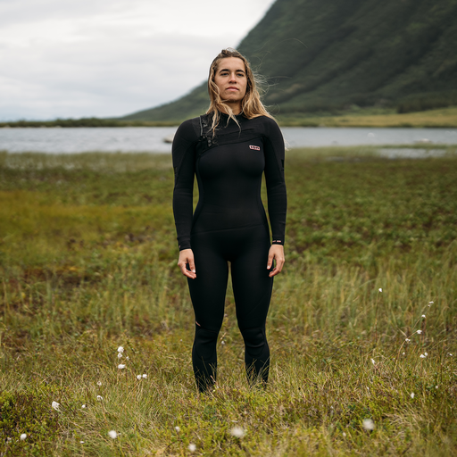 ION Amaze Amp 4/3mm front-zip women's fullsuit in black worn in a Nordic coastal landscape