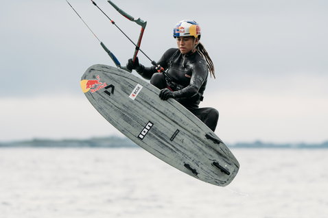 ION Amaze Amp 3/2mm front-zip women's fullsuit in black during kitesurfing on the ocean