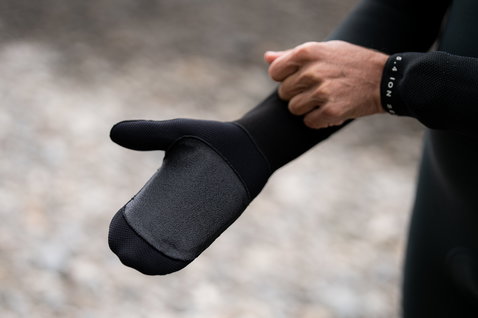 ION Arctic Mitten 5/4 neoprene mitten glove in black being put on at the shoreline
