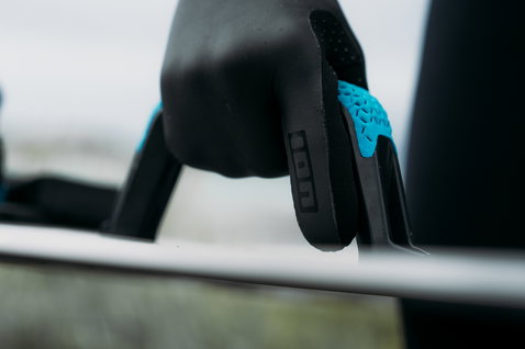 ION Lobster Mitten 4/3 neoprene gloves in black and cyan during wave riding at the coast