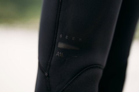 ION Seek Amp 5/4mm back-zip men's fullsuit in black – branding and knee panel detail