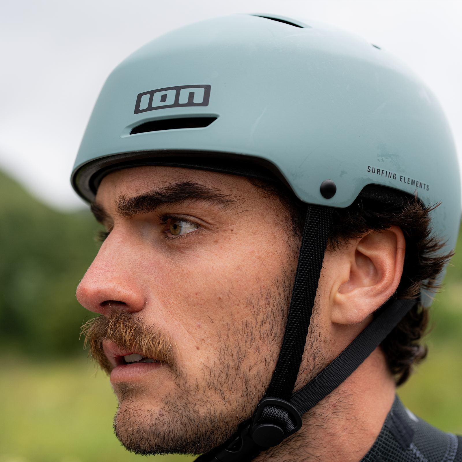 ION Slash Core watersports helmet worn on model in sage green outdoors
