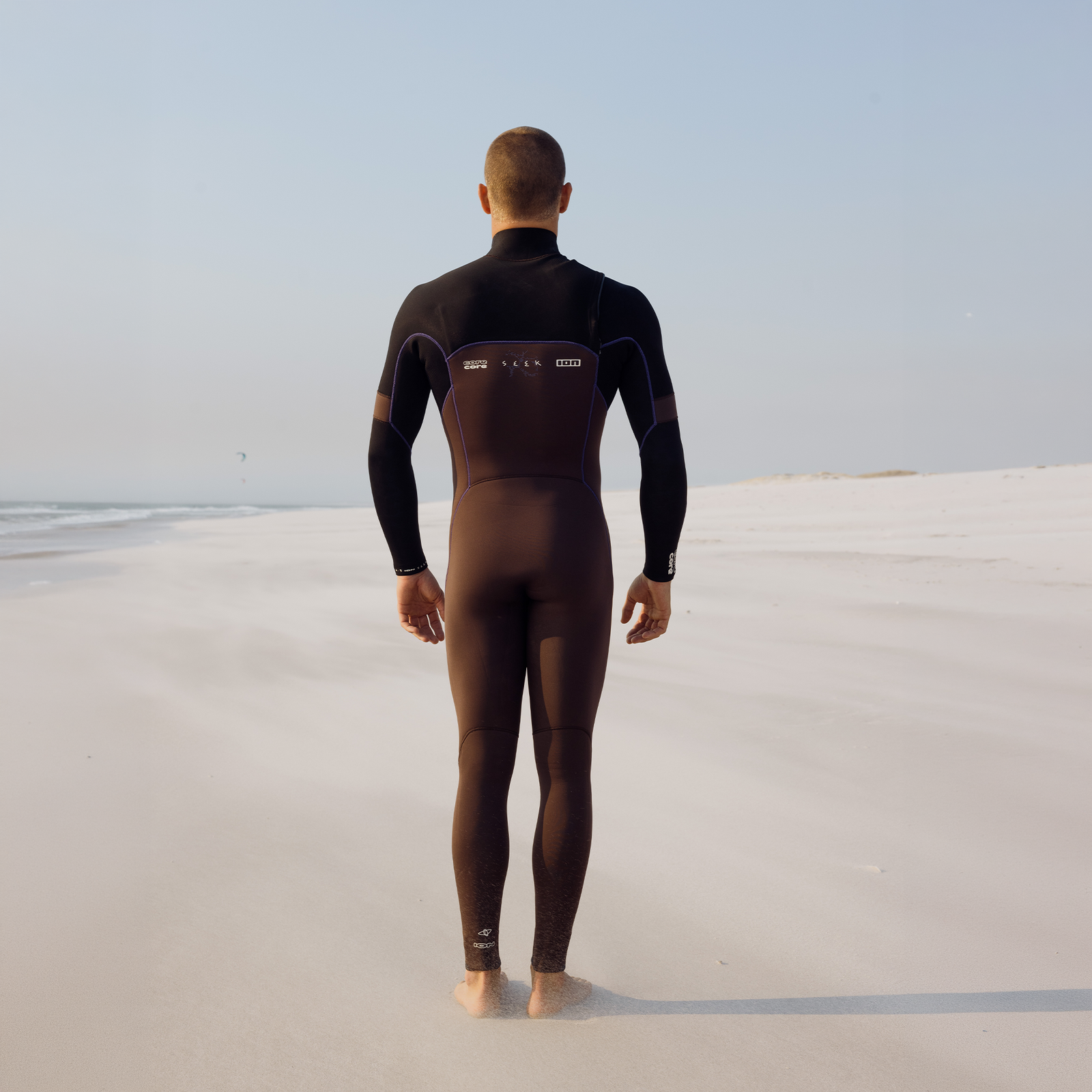 ION Seek Core 3/2mm front-zip fullsuit men in dark brown-black on the beach