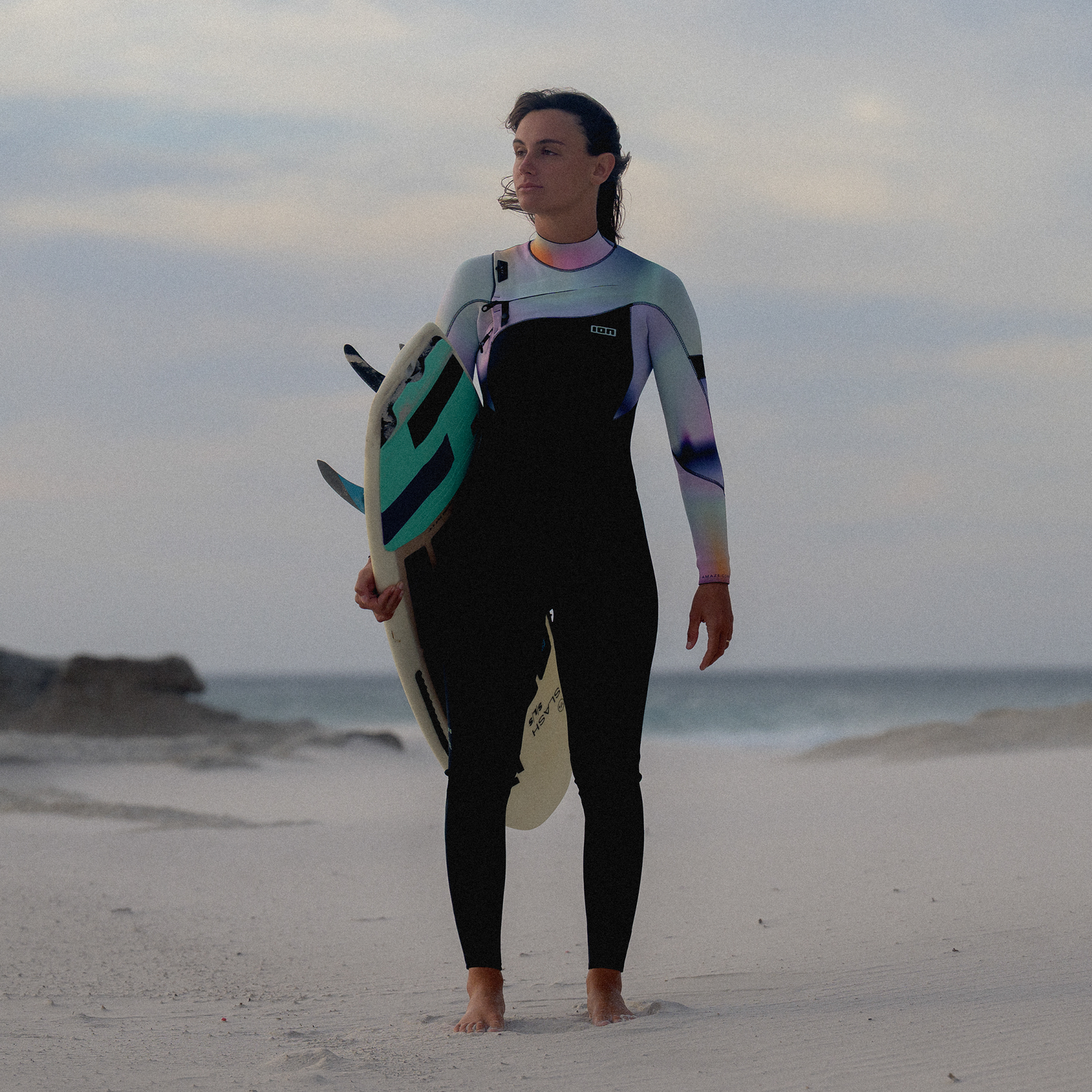 ION Amaze Core 4/3mm front-zip fullsuit women in black with teal and purple during wave surfing at the beach