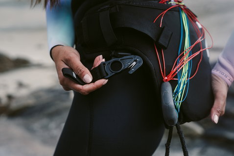 ION Jam waist harness in black with line cutter tool and line storage pocket during wing foiling at the beach