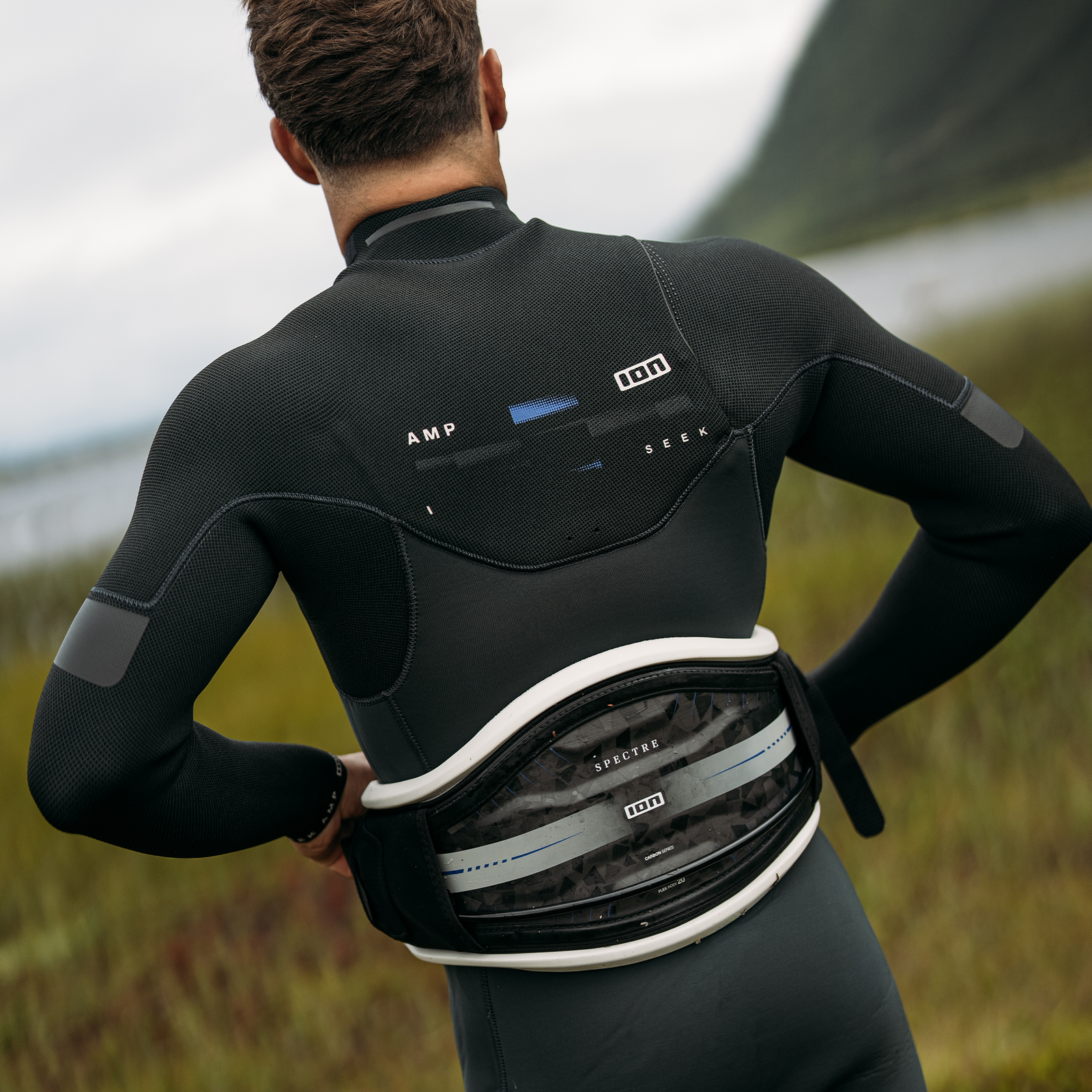 ION Spectre Hüfttrapez in schwarz mit Carbon-Hardshell beim Kitesurfen an der Küste
