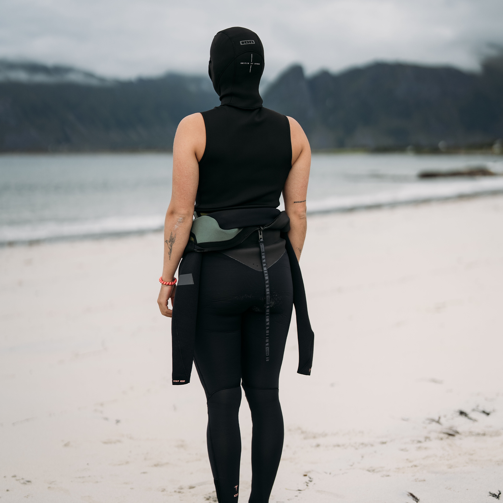 ION Neo Top Hooded Vest 2/1mm veste en néoprène à capuche en noir lors du kitesurf sur la plage