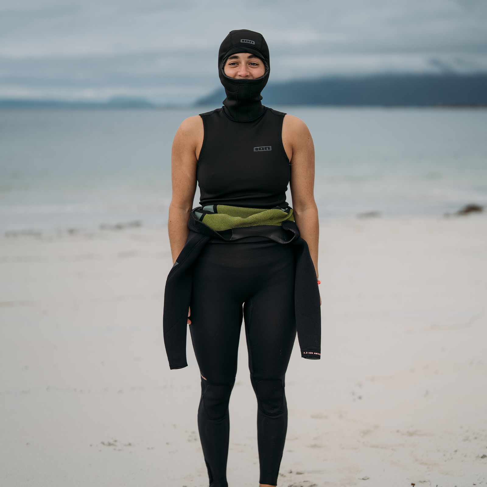 ION Neo Top Hooded Vest 2/1mm veste néoprène à capuche en noir sur la plage