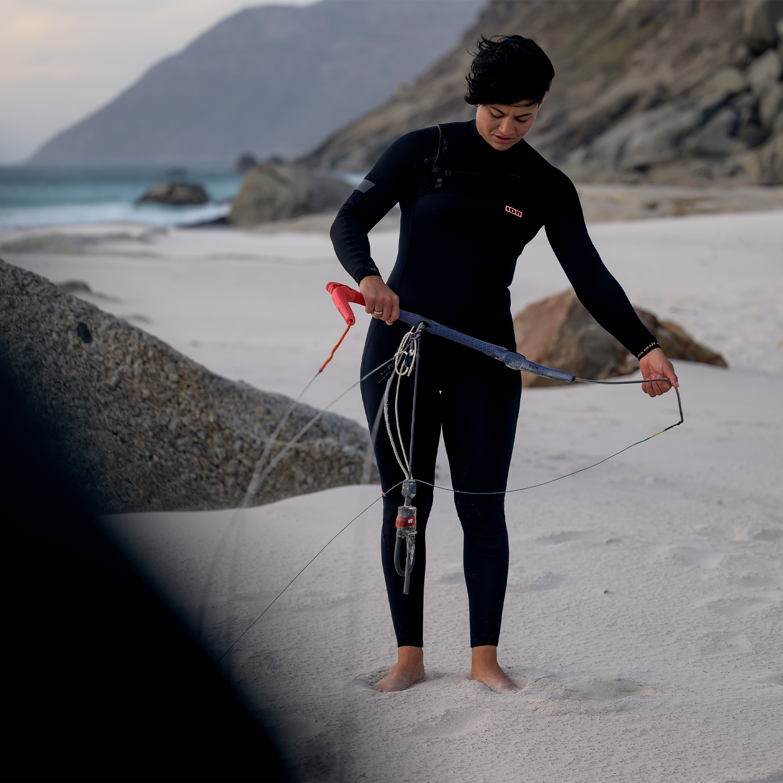 ION Amaze Amp 4/3mm front-zip women's fullsuit wetsuit in black during kitesurfing on the beach