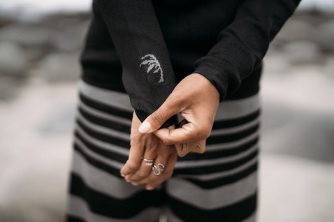ION Surf Shield rashguard unisexe à manches longues en noir – détail poignet lors du surf en bord de mer