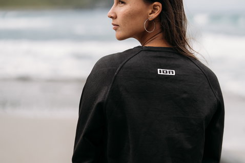 ION Surf Shield wetshirt manga comprida em preto, vista traseira vestido em modelo na praia