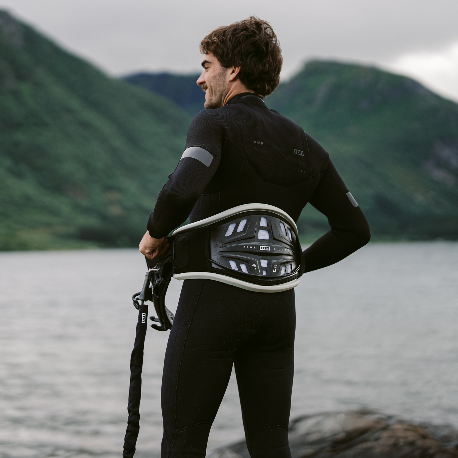 ION Seek Amp 4/3mm front-zip fullsuit for men during kitesurfing at a fjord in black